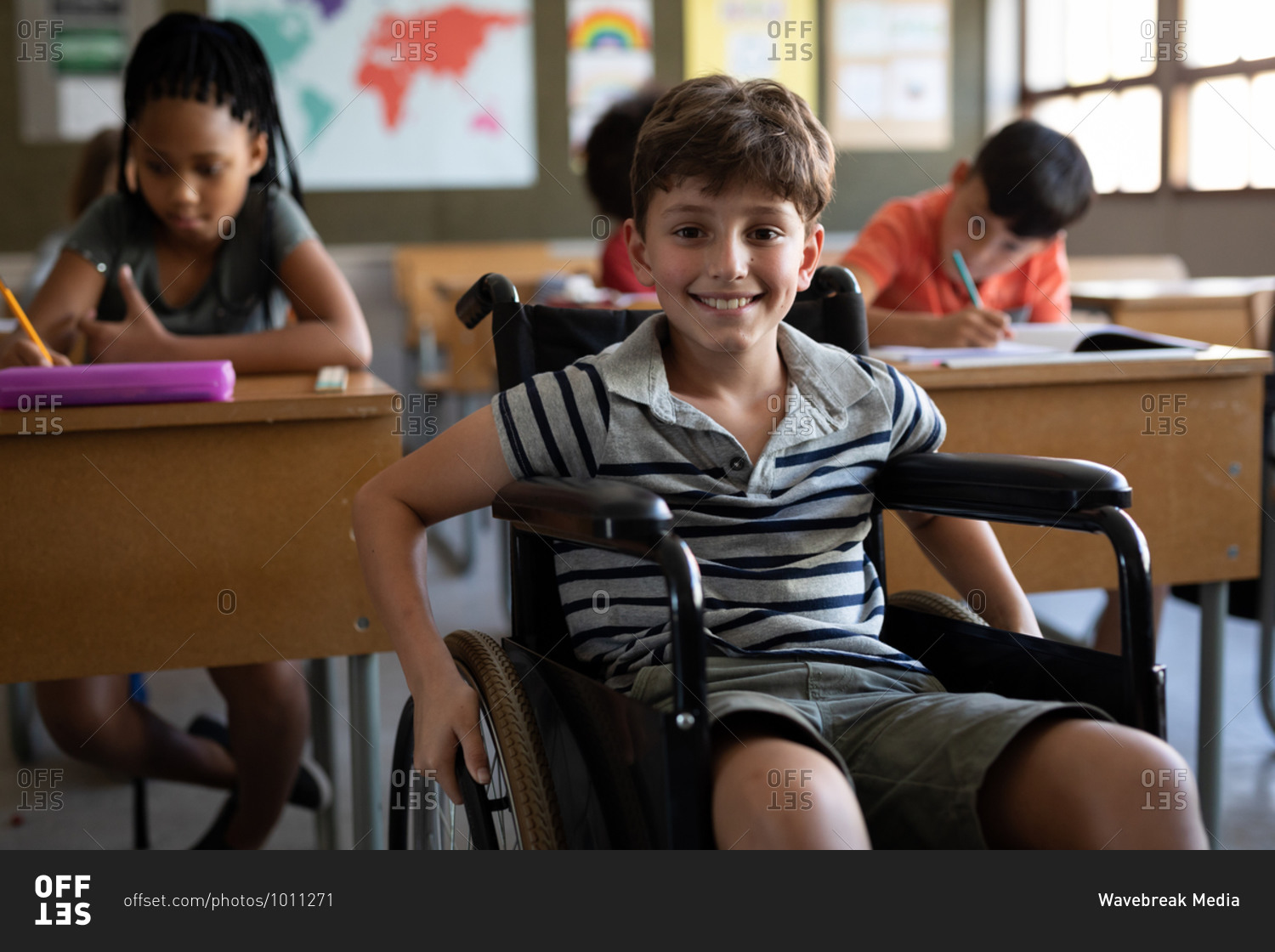 Portrait of disable Caucasian boy sitting in his wheelchair in the classroom during the lesson.  Primary education social distancing health safety during Covid19 Coronavirus pandemic.