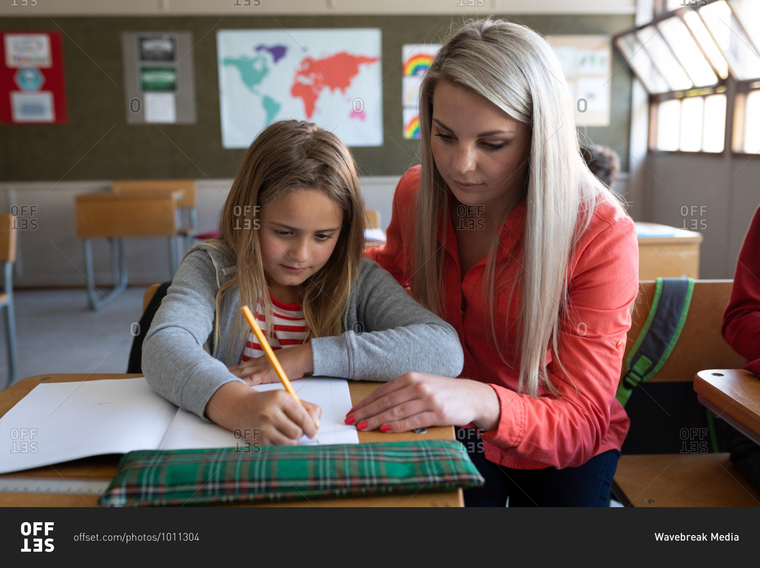 Female Caucasian teacher teaching a Caucasian girl during the lesson. Primary education social distancing health safety during Covid19 Coronavirus pandemic.