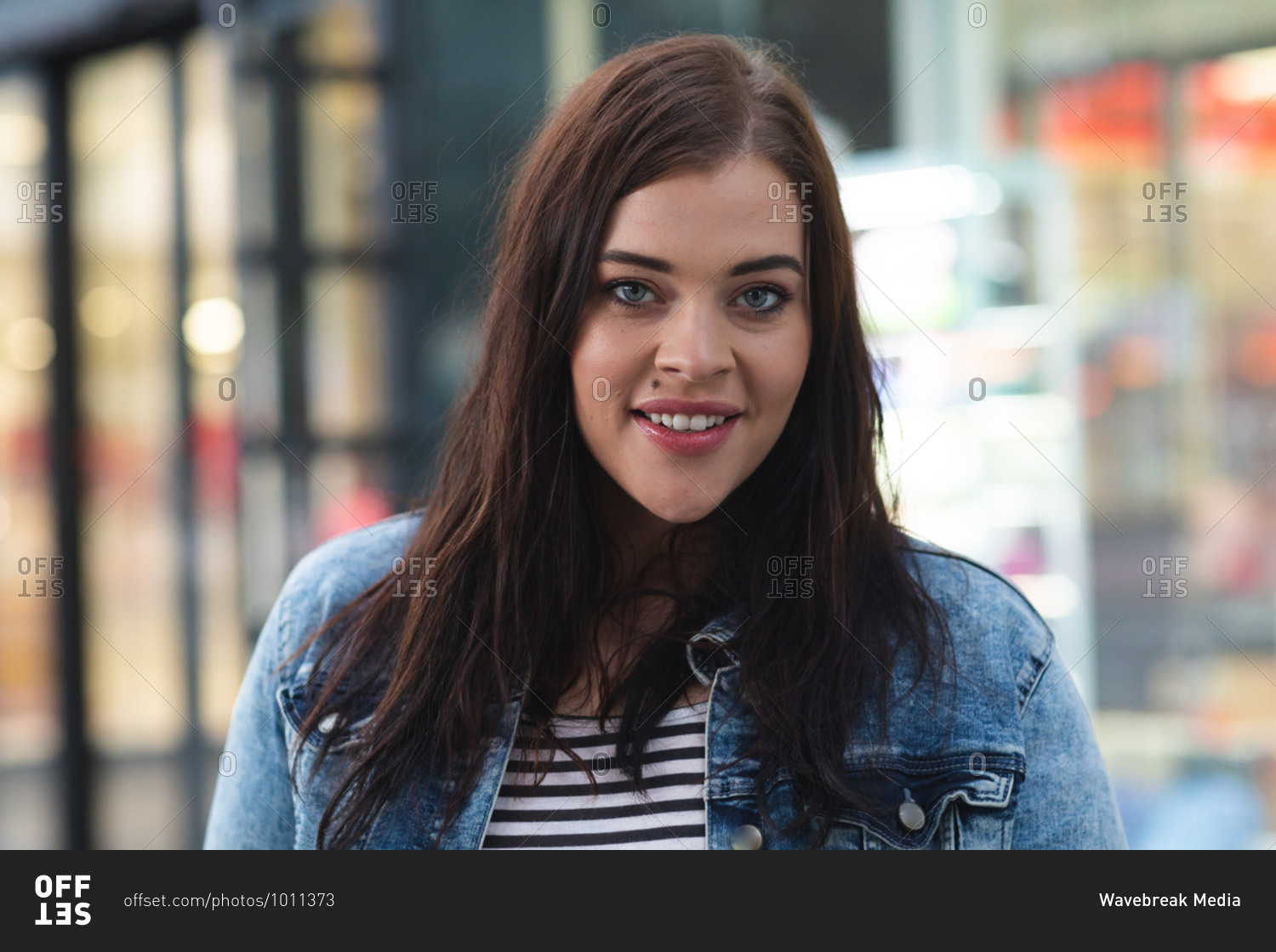 Portrait of a curvy Caucasian woman out and about in the city streets during the day, looking to camera and smiling with modern building in the background