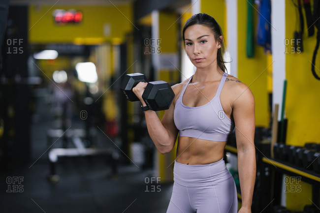 Beautiful woman exercise biceps with dumbbells at gym