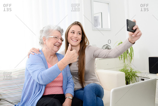 Old senior woman making a selfie with her young granddaughter at home