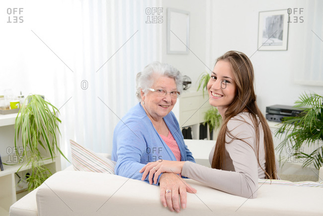 Old senior woman at home with cheerful young girl spending time together