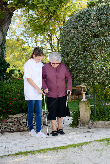 Elderly senior woman with a nurse walking outdoor in nursing home hospital garden