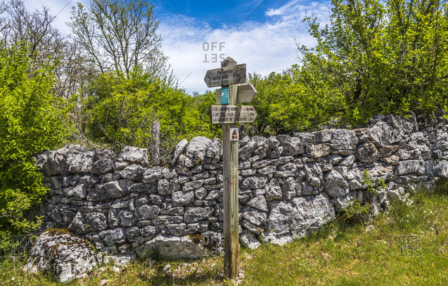 France, Lot, Causses regional Natural Park of Quercy, Natural Sensitive Space of Brauhnie, small dry stone wall of an ewes park and signs indicating the hiking trails