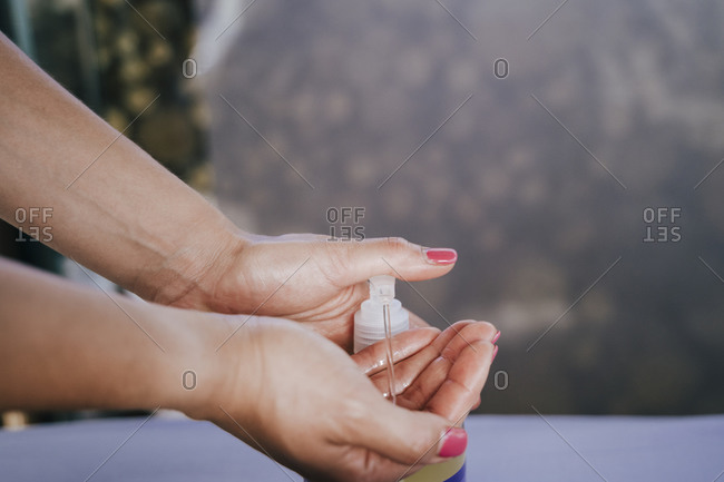 Close-up of female therapist hands taking massage oil from bottle in spa