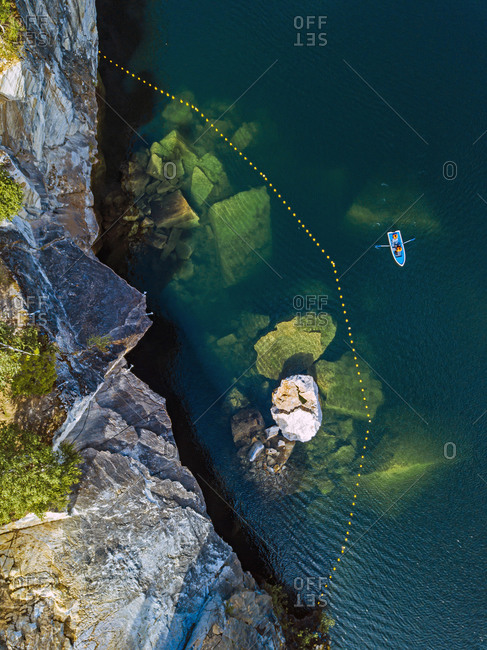 Russia- Republic of Karelia- Ruskeala- Aerial view of boat in front of marble cliff on edge of Marble Lake