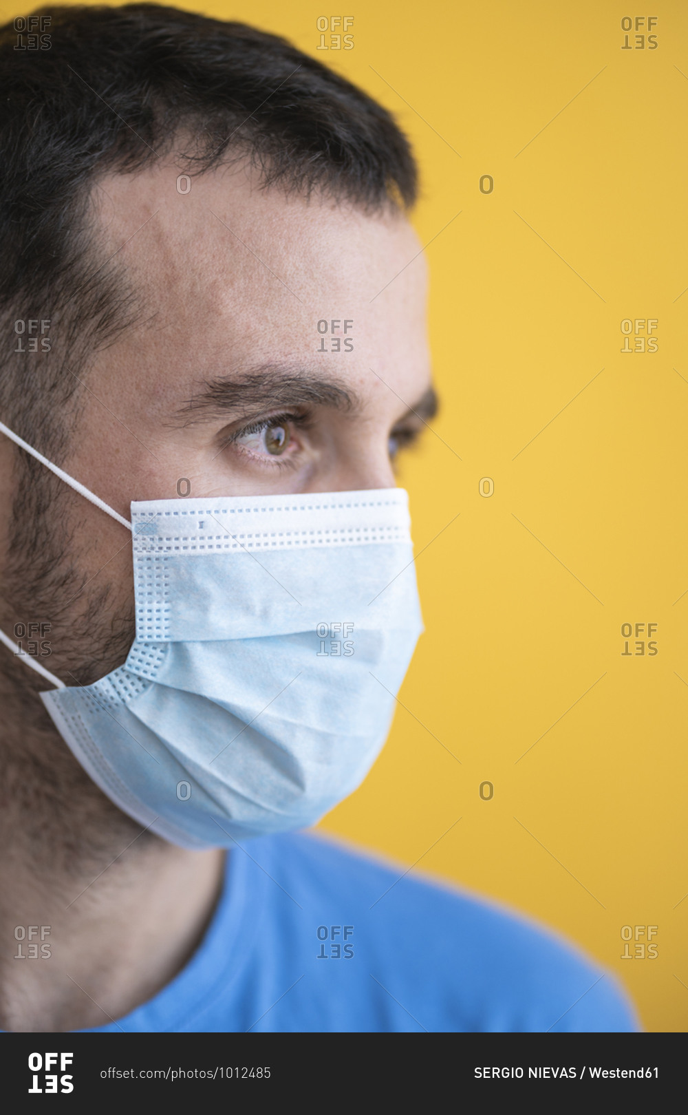 Close-up of thoughtful mid adult man wearing mask against yellow background