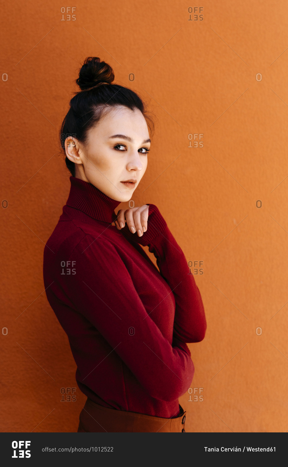 Young woman wearing turtleneck long-sleeved top against orange wall