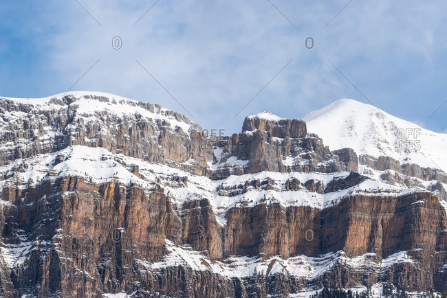 Spectacular landscape of mountain with snowy peak on slope under blue cloudy sky in sunny autumn day