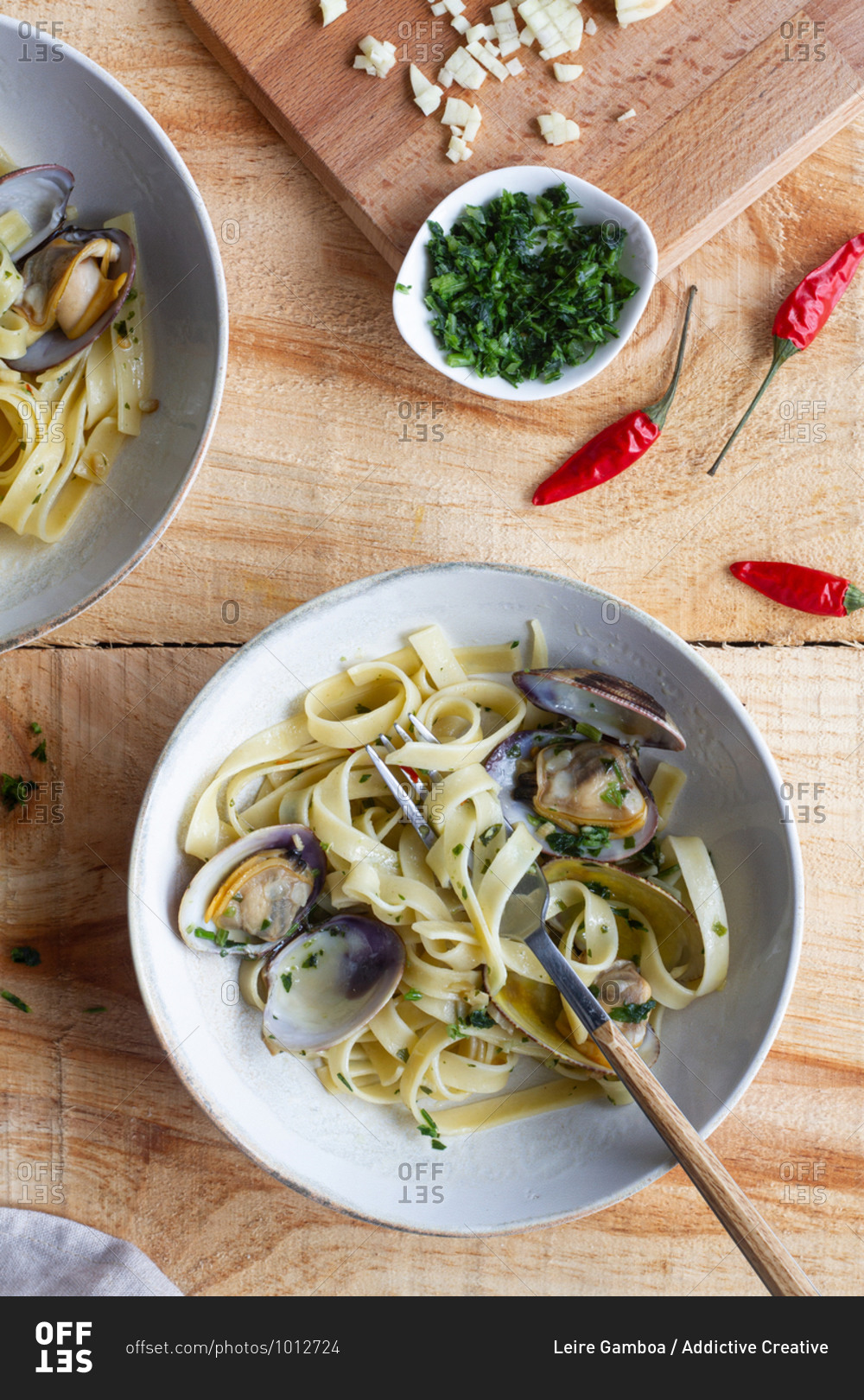 High angle of bowl of freshly cooked spaghetti with clams placed on wooden table in cafe