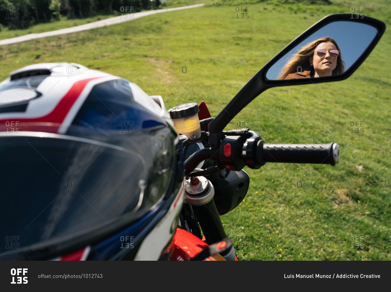 Female motorcyclist sitting on modern bike and enjoying amazing highland landscape on sunny day