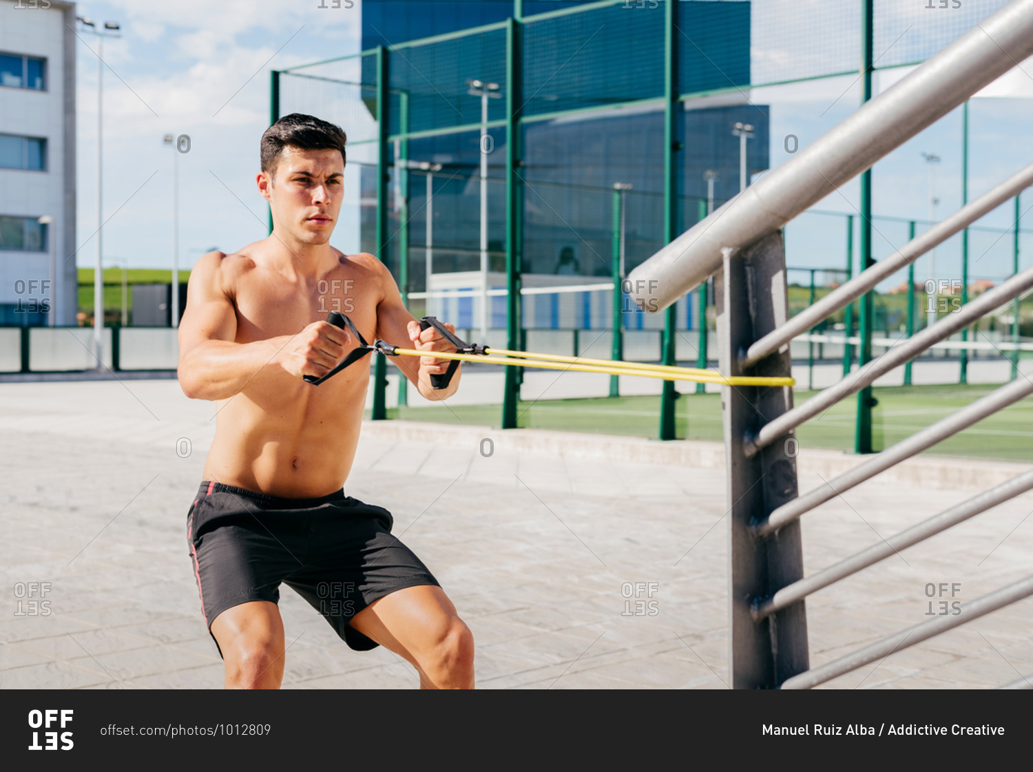 Focused Shirtless Male Athlete Doing Exercises With Elastic Band During Training In City In