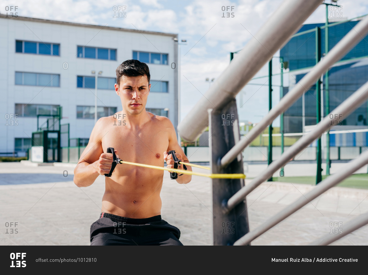 Focused Shirtless Male Athlete Doing Exercises With Elastic Band During Training In City In