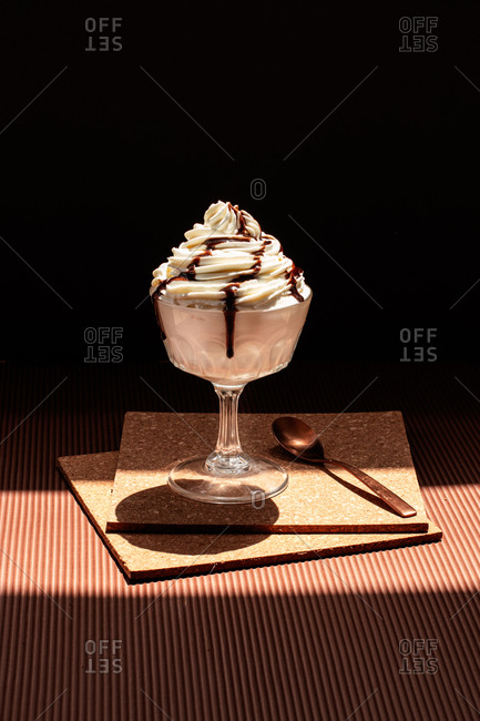 Chocolate ice cream topped with cream and chocolate sauce placed on cork coasters on table