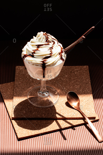 Chocolate ice cream topped with cream and chocolate sauce placed on cork coasters on table