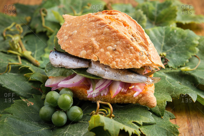 Traditional harvest sandwich with sardines, meat and different vegetables on top of a grapevine leaf. Gastronomy of Canary Islands