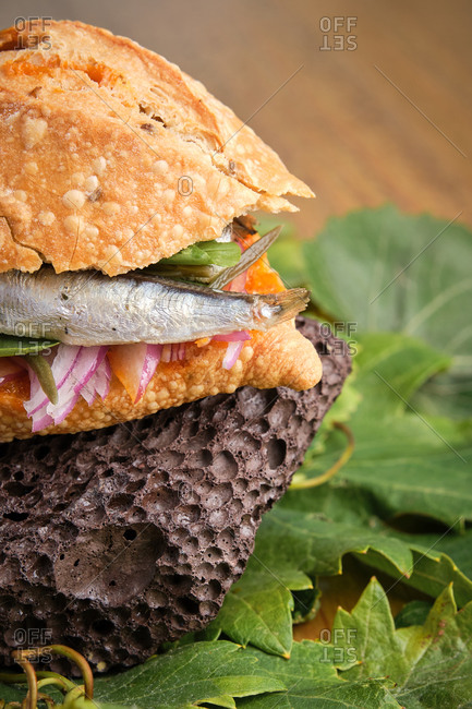 Vertical photo of a detail of the traditional harvest sandwich with sardines, meat and different vegetables on top of a grapevine leaf with a typhoon Gastronomy of Canary Islands