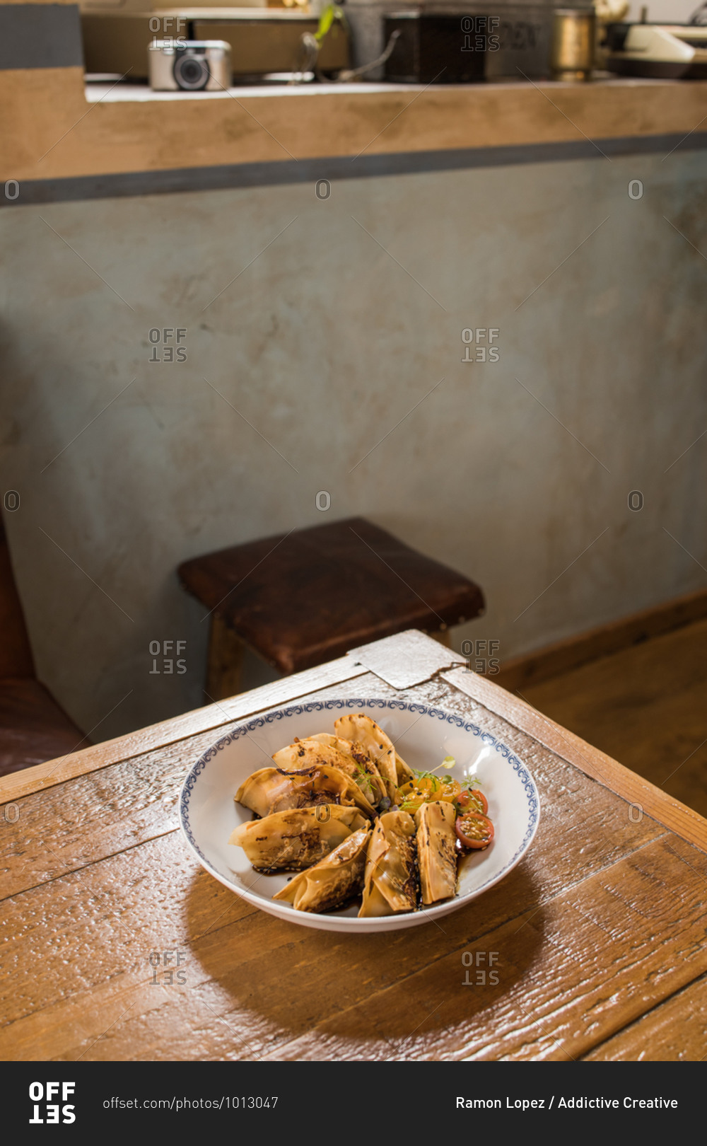 Plate with traditional Asian gyozas filled with vegetables and served with Sriracha hot sauce with mustard and soy on wooden table