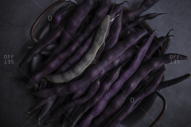 Close up of fresh purple peas on a tray on dark gray concrete surface