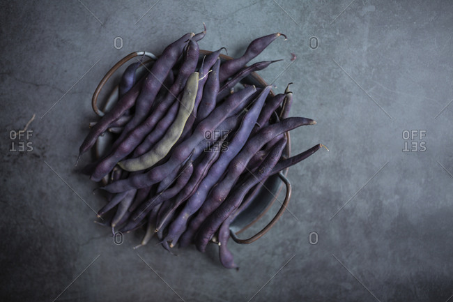 Fresh purple peas on a tray on dark gray concrete surface