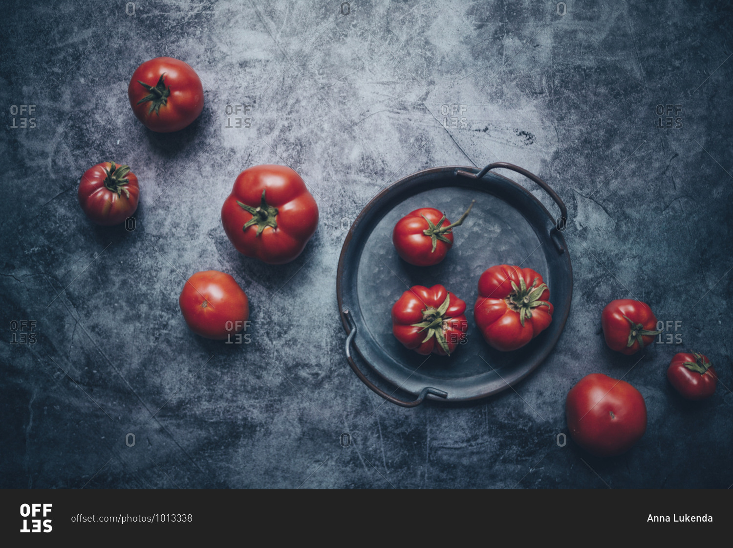 Overhead view of fresh tomatoes in a tray on dark gray concrete surface