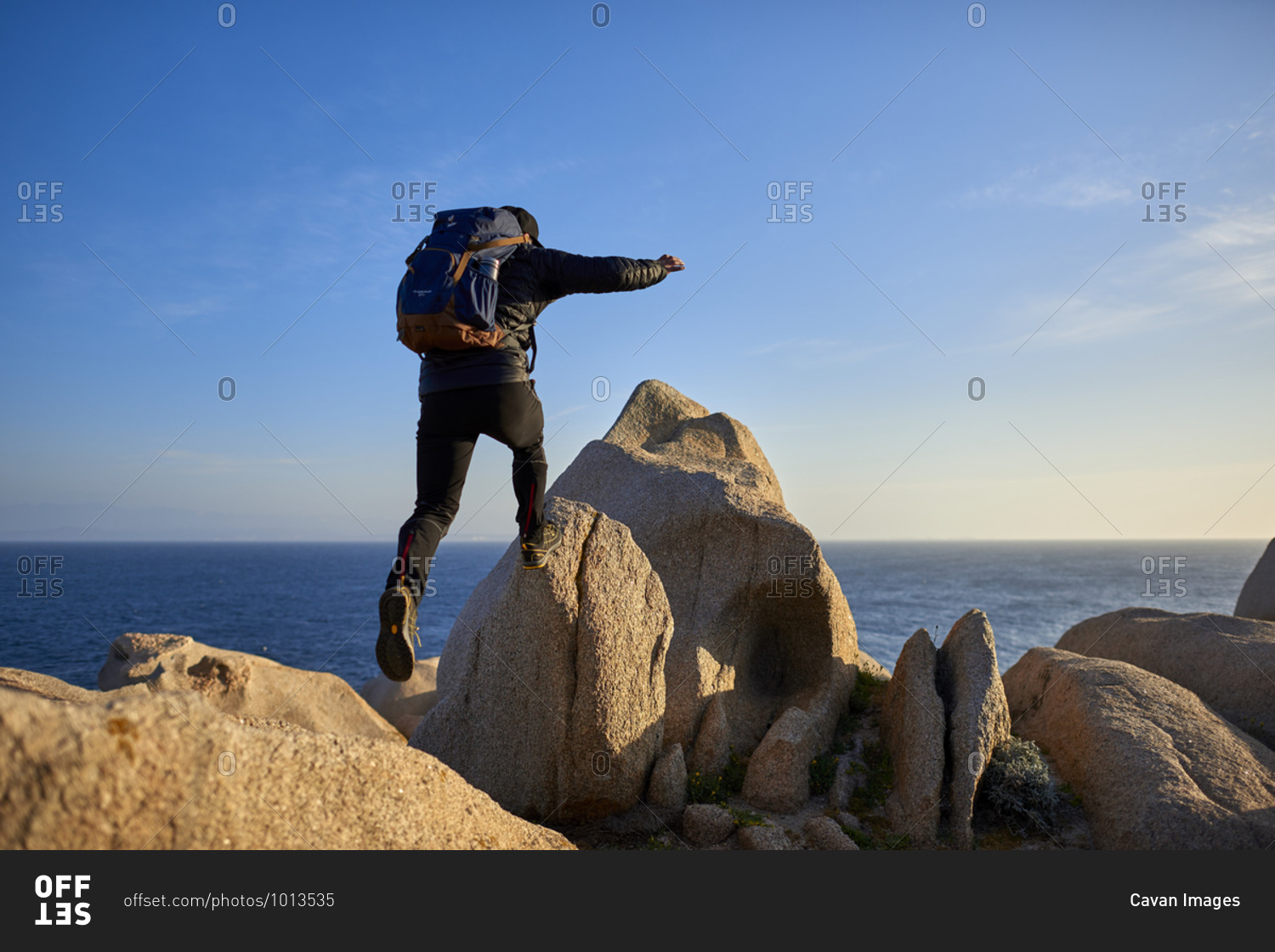 View of man jumping from rock to rock, Sardinia, Italy