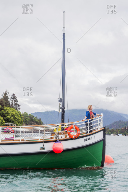 USA, Alaska, Halibut Cove - July 8, 2015: A woman stands on the front of a green boat in Halibut Cove, Alaska.