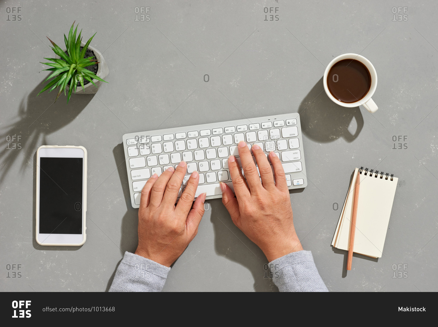 Man typing on modern office desk with keyboard and other supplies with cup of coffee with copy space