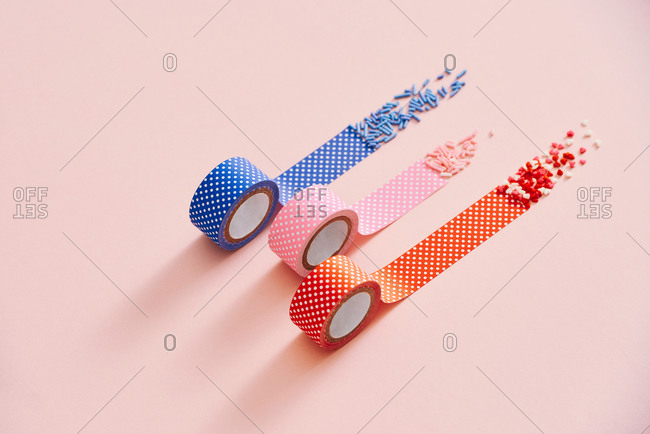Colorful sprinkles and polka dots tape isolated on a pink background
