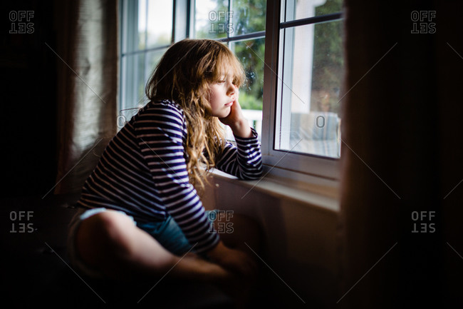 Young girl staring out the window in boredom