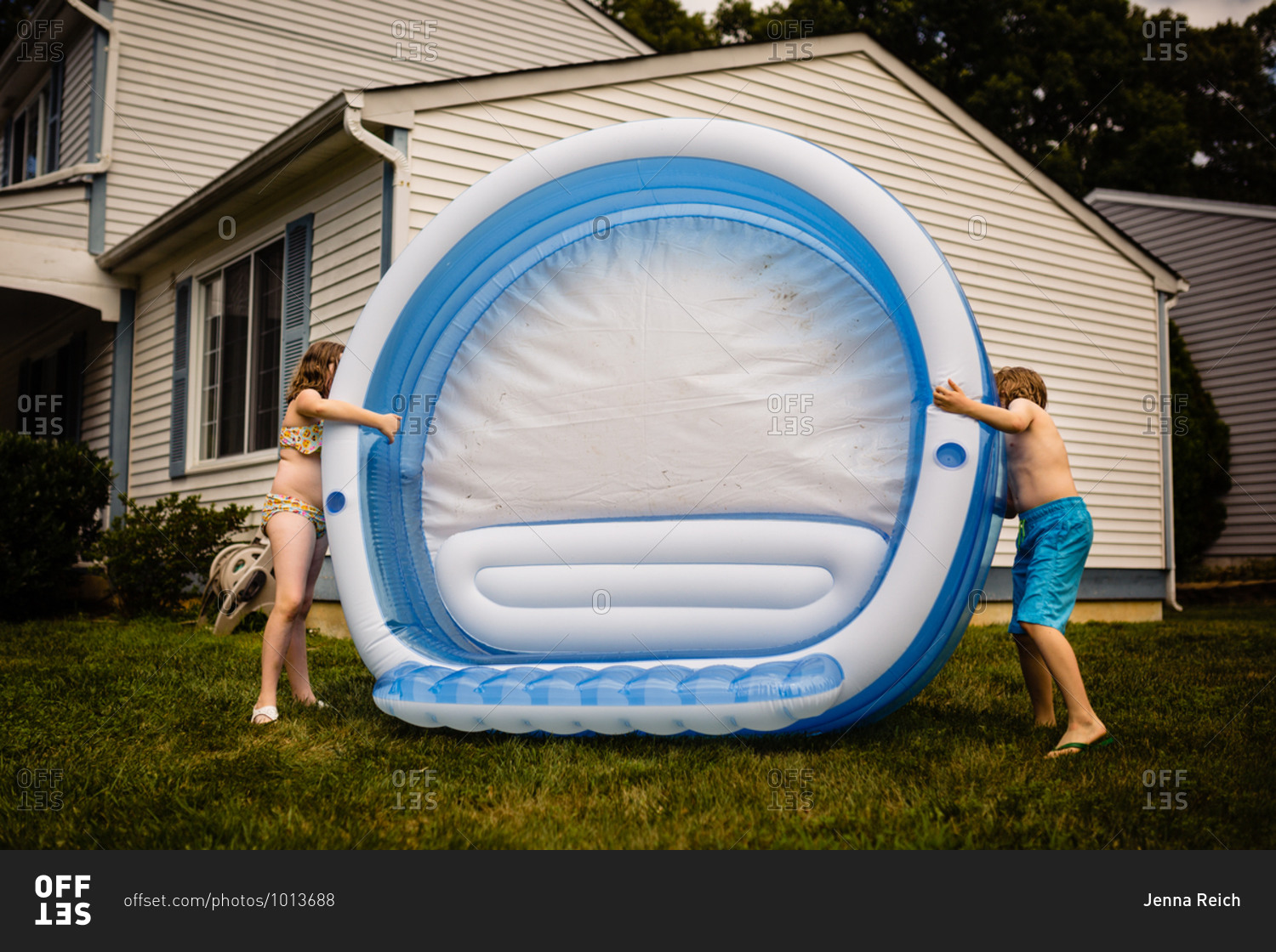 Two kids setting up an inflatable pool in their front yard