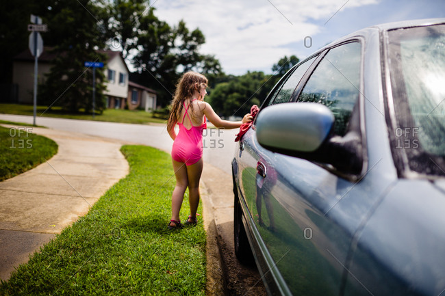 Young girl washing a car in the summertime