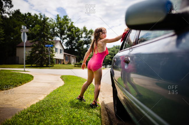 Little girl washing a car in the summertime