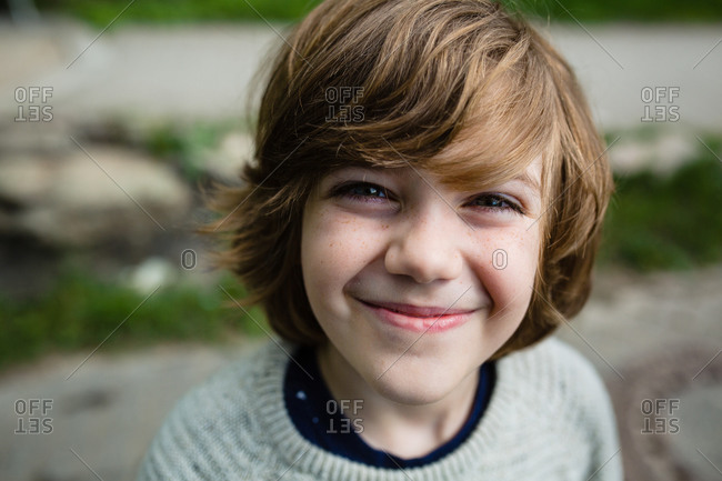 Portrait of a young boy with light brown hair and freckles smiling stock  photo - OFFSET