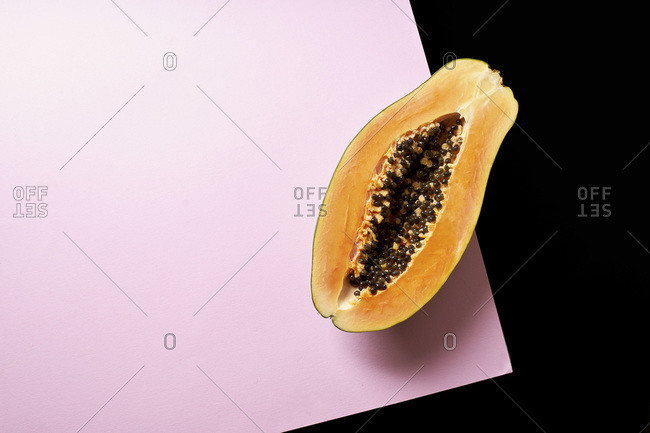 Still life composition with papaya on pink and black background.