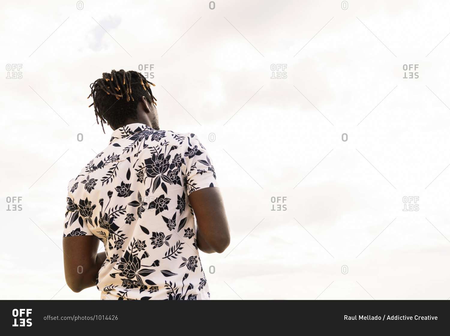 Back view of a stylish young african american man in a flower shirt with the sky in the background, concept of freedom and lifestyle