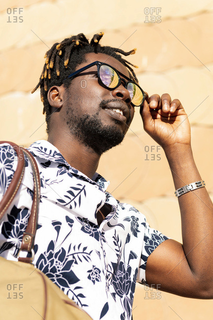 Vertical portrait of a stylish young black man wearing sunglasses, concept of freedom and traveler lifestyle