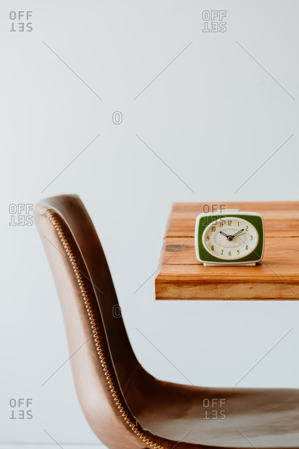 Vintage alarm clock placed on old lumber table in bright living room in apartment