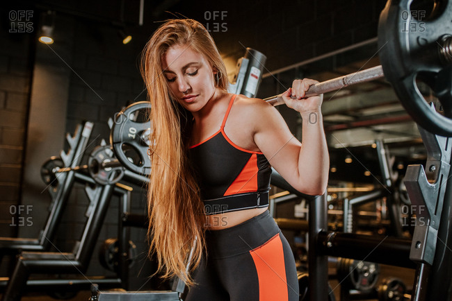 Strong focused confident calm sportswoman athlete in sportswear working out with barbell in sport club