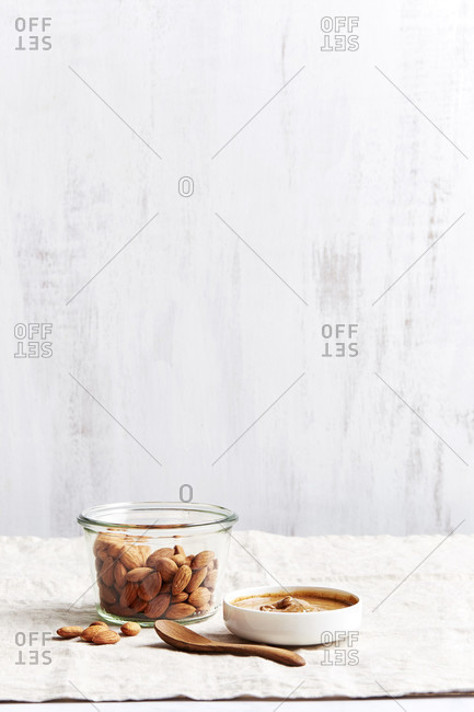 Jar of almonds with almond butter and a wooden spoon