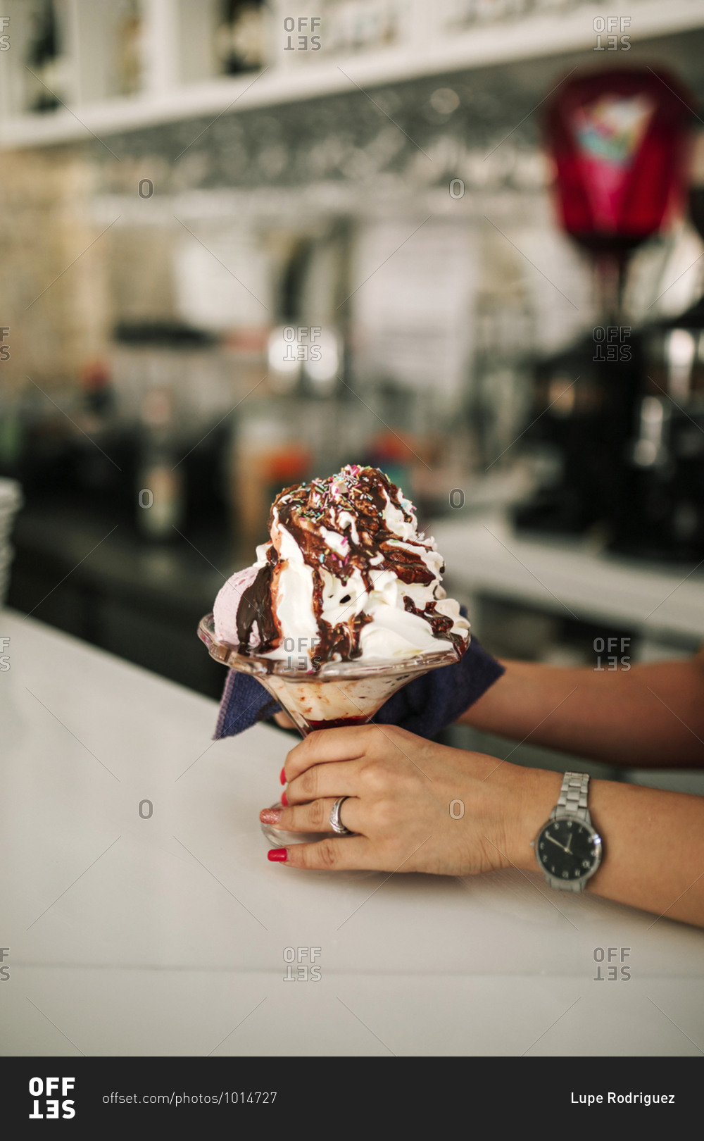Woman\'s hands holding a sundae in ice cream parlor