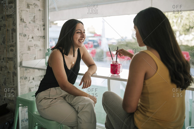 Two young women having a frozen shake in an ice cream parlor