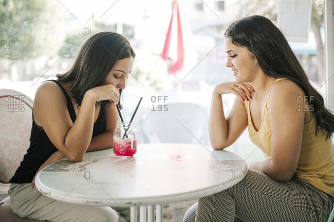 Two young women having a frozen shake in an ice cream parlor