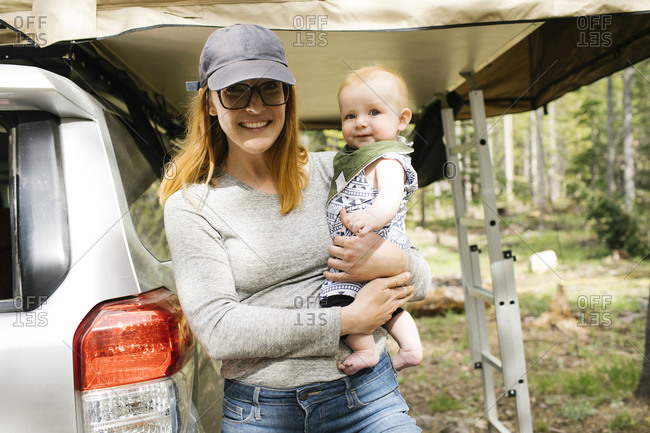 Portrait of smiling woman with baby son (6-11 months) on camping Wasatch-Cache National Forest
