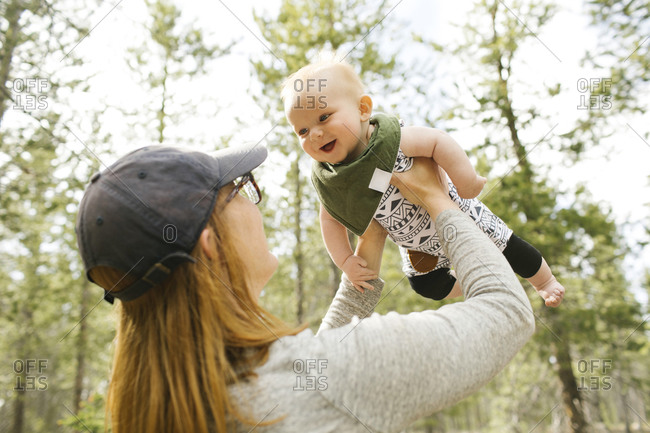 Smiling woman playing with baby son (6-11 months) in forest, Wasatch-Cache National Forest