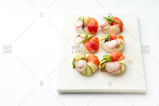 Sushi donuts with salmon and crunchy vegetables on marble cutting board. Top view with copy space.