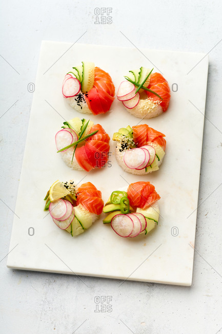 Sushi donuts with salmon and veggies on marble cutting board