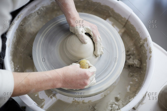 Cropped hands of woman molding pot in art class