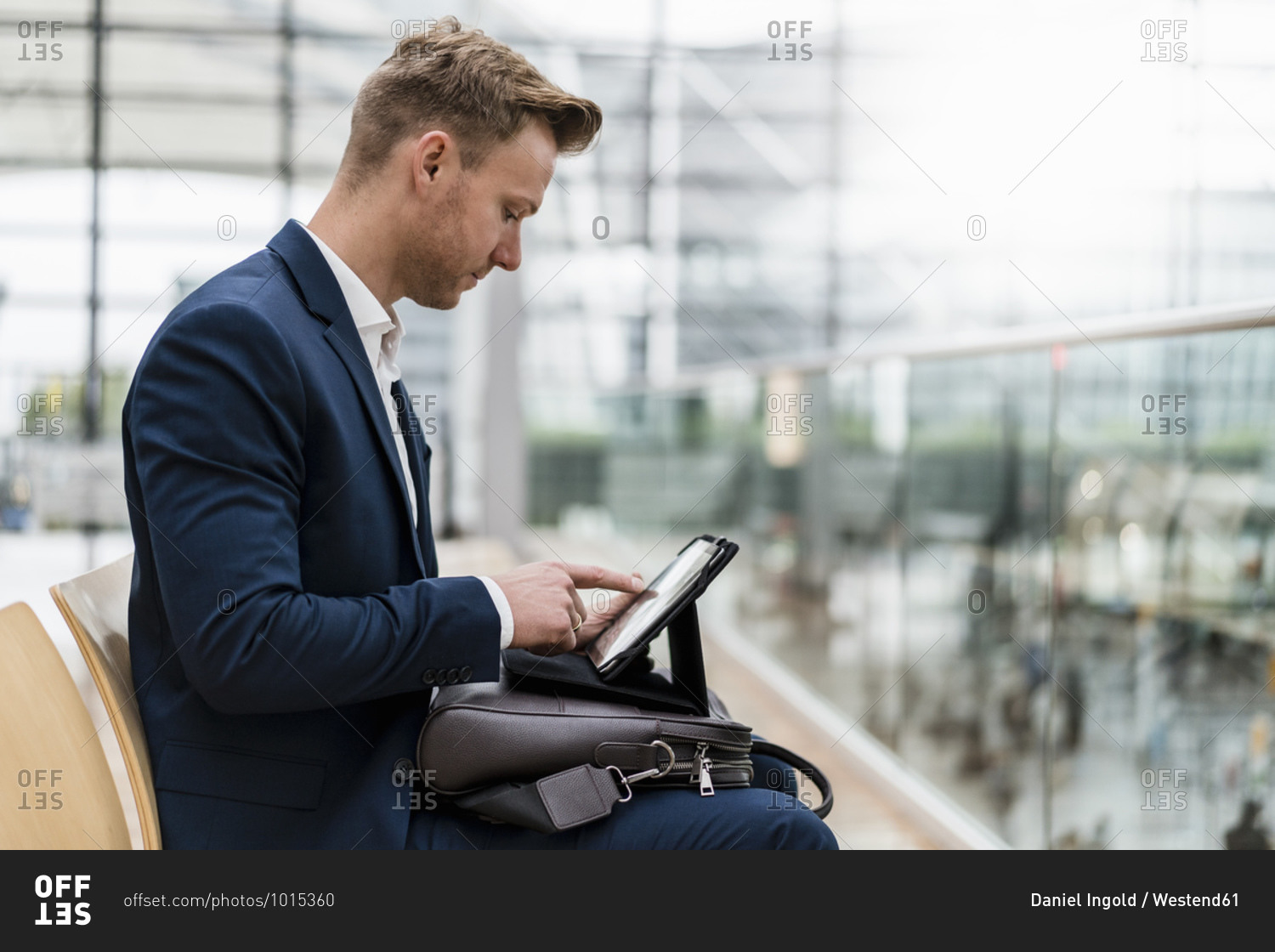Businessman with bag using digital tablet while sitting in city
