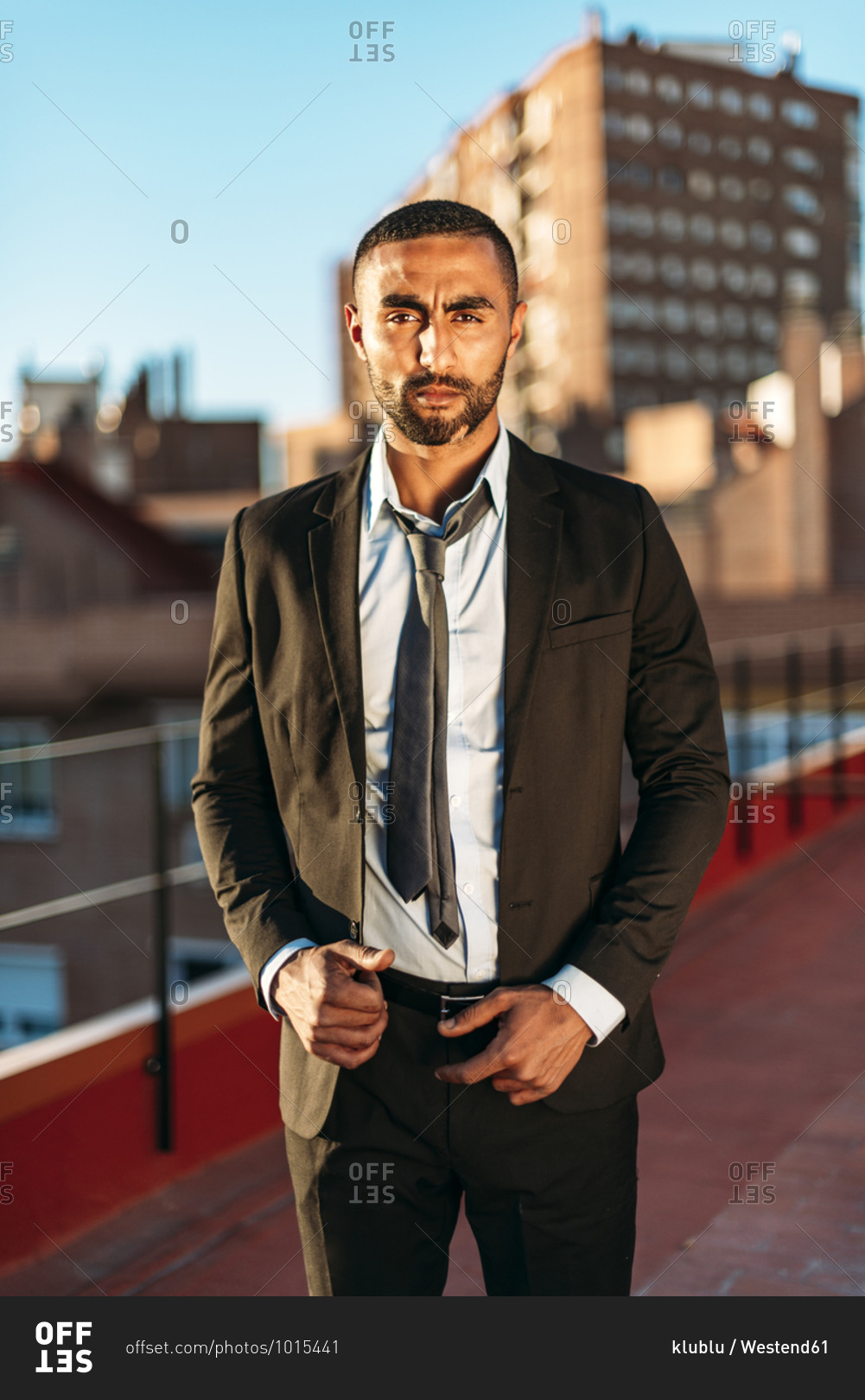 Well-dressed young male entrepreneur standing on rooftop in city